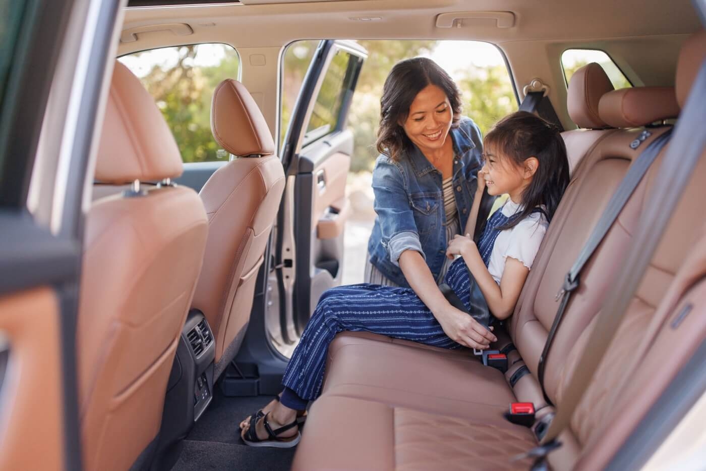 Mère attachant la ceinture de sécurité à sa fille à bord du Nissan Rogue 2025.