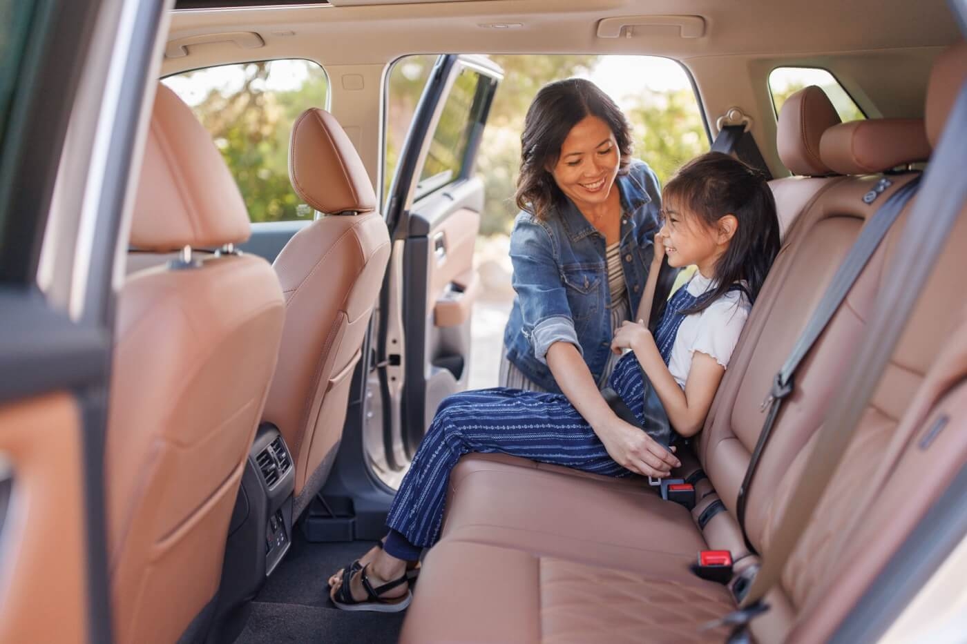 Mère attachant la ceinture de sécurité à sa fille à bord du Nissan Rogue 2024.
