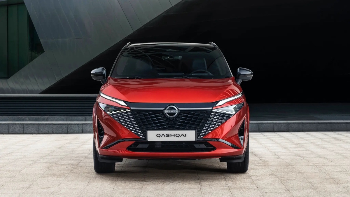Nissan Qashqai 2025 rouge vu de face stationné sur une esplanade urbaine moderne.